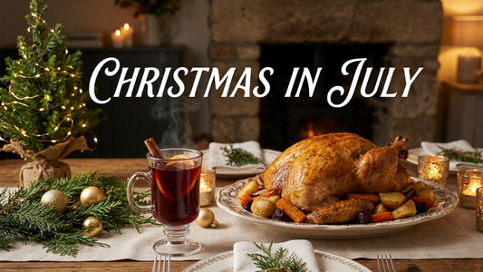 A cozy and elegant Christmas in July dinner table setting featuring a steaming glass of mulled wine, a roasted turkey with vegetables, a small decorated Christmas tree with fairy lights, and candles in a warm, rustic home environment.