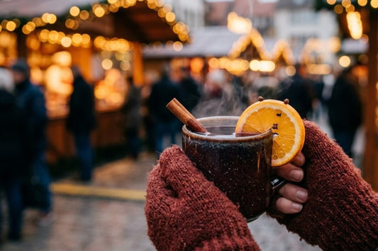 Steaming ceramic mug of Glühwein at a German Christmas market with cinnamon sticks and orange slice