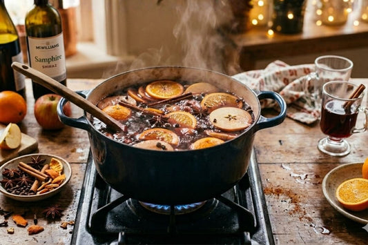 Mulled wine recipe simmering on stovetop with orange slices, apple, cinnamon and star anise