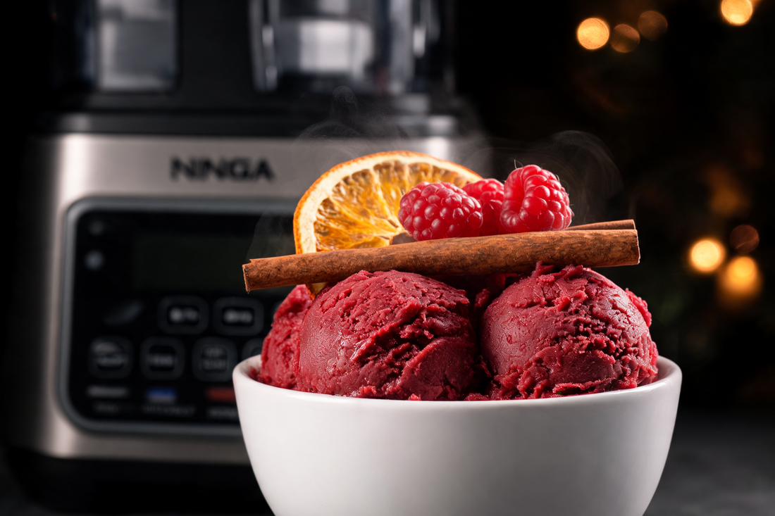 Mulled wine sorbet scoops in a bowl with fresh berries, dehydrated orange garnish and Ninja Creami in the background