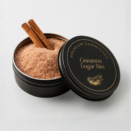 An open round black tin of cinnamon sugar rim garnish with two cinnamon sticks, shown next to its black lid on a clean white background. The lid features gold lettering that reads 'PREMIUM GARNISHES Cinnamon Sugar Rim'.